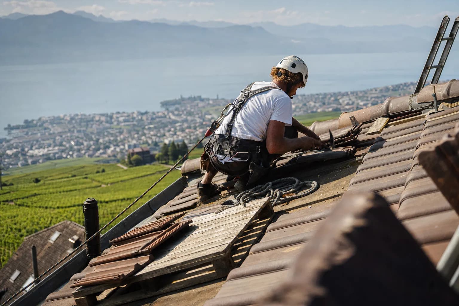 Couvreur sur le toit d'une villa des hauts de Vevey, vignes et lac en contrebas