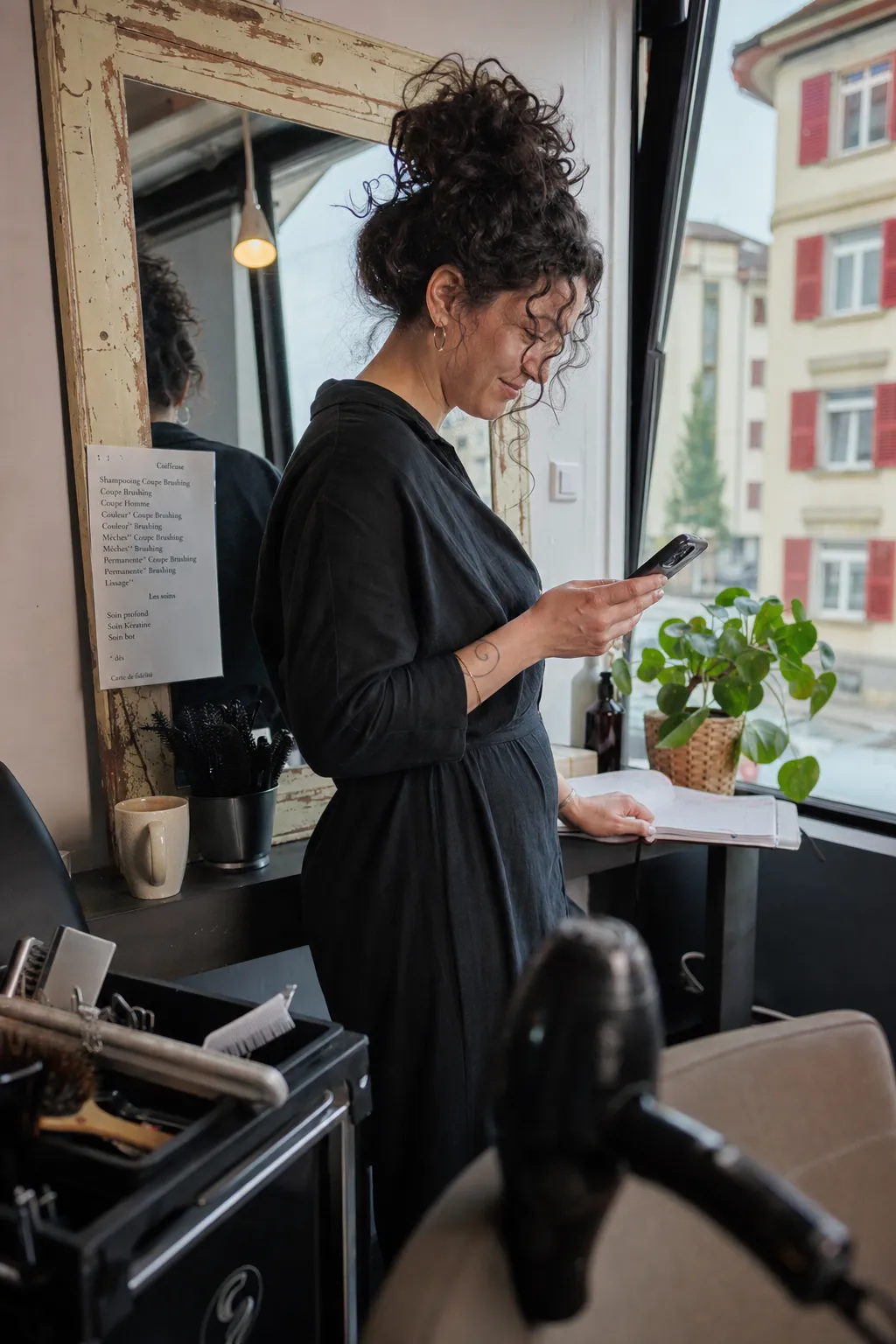 Coiffeuse lisant un message derrière le comptoir de son salon, Sion